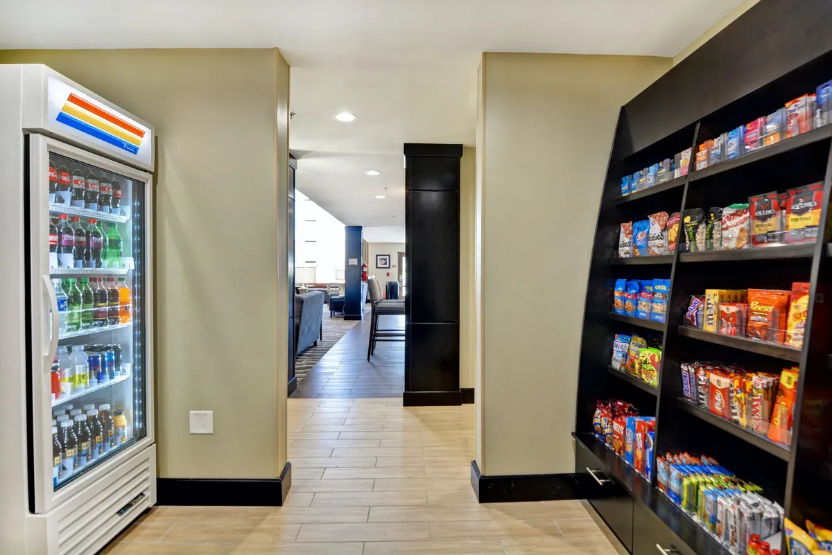 A casual snack area with a vending machine, snack shelf, and a hallway leading to a lounge. This space is easily accessible and convenient for families grabbing quick refreshments or gathering for informal moments.