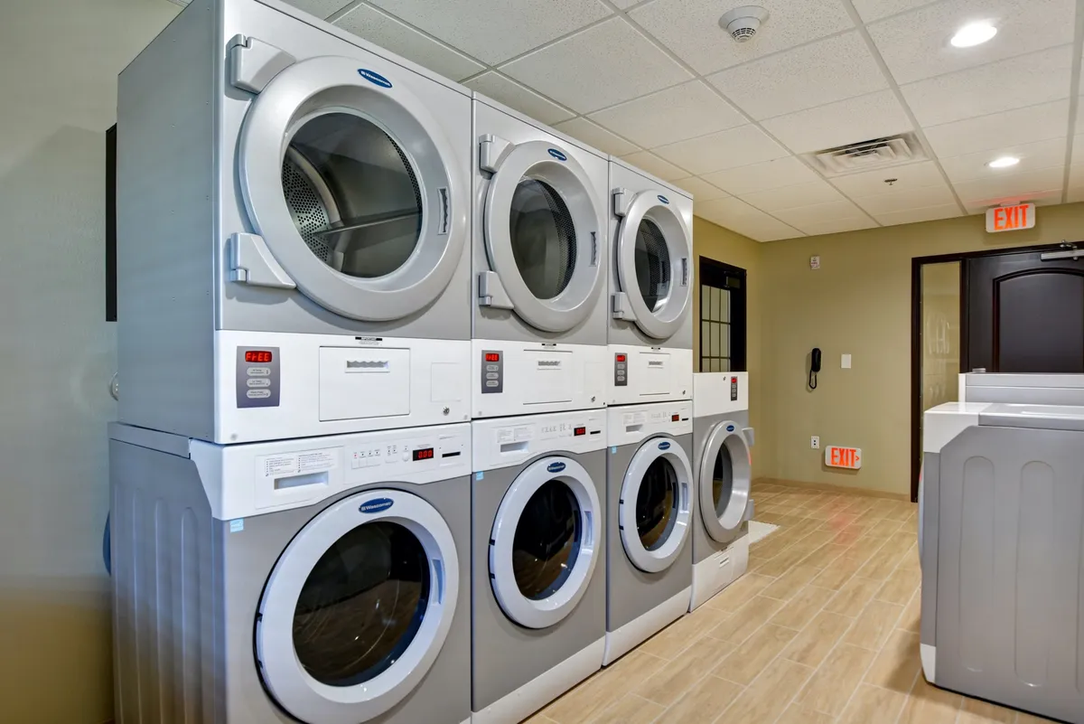 A practical laundry area with stacked washing machines and dryers, plus a dedicated folding area. The design is functional and efficient, providing a self-service convenience to guests.